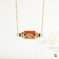 Detail of gold evil eye pendant with WILL engraving and colorful enamel elements - WILL/Evil Eye/Orange Blue