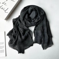 Dark grey modal scarf with fine stripe texture and soft fringe trim on wooden background - Black