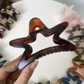 Detail of star-shaped hair claw clip in tortoiseshell finish with a hollow design - 11cm / Matte Red Brown