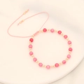 Close-up of pink natural stone beads and golden spacers on adjustable woven bracelet - Pink
