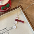 Vue macro d'un pendentif bonhomme de neige avec écharpe rouge sur une chaîne argent - Chaîne Argentée Écharpe Rouge Style Bonhomme de Neige