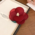 Close-up of a deep red fabric flower hair clip with yellow stamen on a cream jewelry tray - Red Flower Duckbill Clip