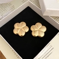 Detailansicht der polierten goldenen Blumen-Ohrstecker auf einer schwarzen Samtbox - Stahlnadel - Gold (umweltfreundlich)