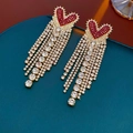 Vue détaillée de boucles d'oreilles à pompon en forme de cœur avec strass rouges - Rouge