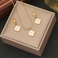 Golden four-leaf clover jewelry set with white enamel and earrings on a beige box - Gold+White