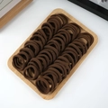 Close-up of brown thick elastic hair ties organized neatly on a wooden display tray - 50 Pieces / Coffee