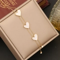 Detailansicht einer goldenen Schlangenkette mit drei weißen Herzanhängern aus Muscheln - Herz Perlmutt Schlangenkette Halskette