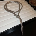 Detailed view of silver snake necklace with sparkling zircon head and green gem eyes - Silver