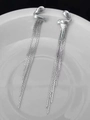 Primer plano de pendientes geométricos con borlas de plata y cadenas sobre cerámica blanca - Plateado