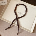 Detail of dark brown fabric necklace with floral pattern and vintage wood bead on tray - Necklace #11 - Brown