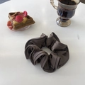 Elegant dark brown satin scrunchie with pleated texture on white table with breakfast - Light Luxury Coffee