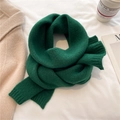 Close-up of soft dark green knitted scarf artistically folded on a minimalist white surface - Forest Green