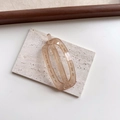 Primer plano de pinza ovalada ámbar translúcida sobre un pedestal de piedra blanca - Ovalado Champaña