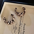 Detailed view of leopard print C-shape earrings with gold studs inside a jewelry box - Style 30: Coffee Leopard Fabric C-Shaped Hoop Earrings with Silver Earring Post