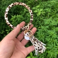 Leopard print PU leather bangle keychain with tassel and gold metal clasp held in hand - Tiger Print