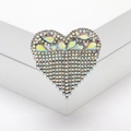 Dettaglio della spilla a cuore con strass e catena a nappe su piedistallo bianco - Argento