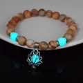 Luminous lotus flower bracelet with marble stones glowing in orange and aqua on white plate - 8mm Natural Red Network Stone with Blue-Green Light