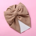 Detailed macro view of camel knitted baby turban hat with a large decorative bow - One Size / Khaki