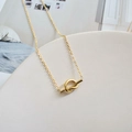 Detailed view of a gold knot pendant necklace on a white elegant jewelry display - Gold
