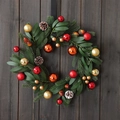 Christmas wreath with red and gold balls, pine cones and needles on dark wooden door - Style 25-26