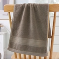 Thick dark brown cotton towel with stripe trim displayed on a wooden chair - Cotton Gold Ribbon Grey (Towel)