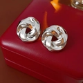 Macro shot of silver twisted knot earrings placed on a premium red leather jewelry box - Silver