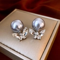 Macro shot of gray pearl earrings with crystal butterfly drop on silver jewelry box - Silver Butterfly Rhinestone Grey Pearl Studs