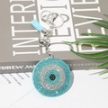 Detail eines blauen Evil-Eye-Schlüsselanhängers mit Strasssteinen, Glocke und Quaste - Seeblau