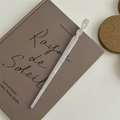 Dettaglio di un fermaglio per capelli bianco perlato su sfondo di un libro vintage - Bastoncino per Capelli Intrecciato