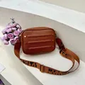 Detail van caramelbruine crossbodytas met klinknagels en Paris-logo schouderriem - Bruin