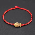 Detail view of a red woven rope bracelet with a carved yellow fish-shaped charm - Small Fish Accessory / Red
