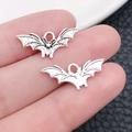 Pair of silver bat-shaped metal charms for DIY jewelry making held on fingertips - Tiny Bat 21x9mm