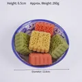 Cinco pasteles chinos sin azúcar en varios colores dentro de un cuenco de porcelana - Pasteles de luna