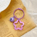 Detail shot of purple star acrylic keychain with bell on vintage newspaper background - Purple