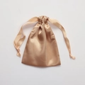 Champagne gold satin drawstring pouch with smooth silk-like texture on white background - Champagne
