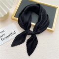 Elegant pleated black silk scarf tied as a bow on a luxury minimalist display - Black