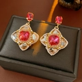 Macro shot of vintage style earrings with red gemstones and white woven details - Silver Pin Gold Magenta