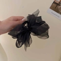 Dettaglio di una molletta per capelli nera con fiocco in tulle tenuta in mano su sfondo - Nero