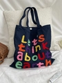 Detail of colorful boucle embroidery text on navy blue canvas tote bag with snap button - Navy Blue