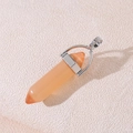 Orange hexagonal crystal point pendant with silver metal bail on neutral background - Orange Cat Eye
