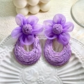 Close-up of purple woven straw earrings with tulle flower petals on a white ceramic plate - Purple