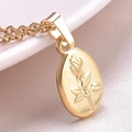 Close-up of golden oval pendant featuring embossed rose floral details on metal surface - Gold---Necklace