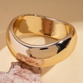 Nahaufnahme eines breiten vergoldeten Armreifs mit unregelmäßigem Design auf Naturstein - Quadratische Form / Gold