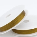 Nahaufnahme von feinem goldenem Perlenfaden auf weißen Spulen für DIY-Schmuckherstellung - 0.3mm x 25m / Gelb