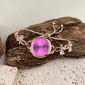 Detail einer roségoldenen Armbanduhr mit lila Zifferblatt und rosa Kristall-Schmetterling - Rosenrot