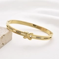 Eleganter Gold-Manschettenarmreif aus Titanstahl mit funkelnden X-förmigen Kristalldetails - Texturiertes X & Strass