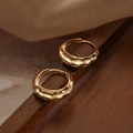 Modieuze gouden C-vormige oorbellen met textuur op een donker houten plateau - Gehamerde Textuur Ring Stijl (44755)