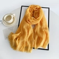Close-up of yellow linen scarf showing wrinkled fabric texture and raw frayed edges - Yellow