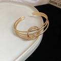 Macro-opname van een gouden gedraaide armband met drie lagen en een ringvormig detail - Goud 3-laags Gevlochten Ringstijl