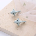 Detailed view of light blue shark stud earrings on a decorative marble surface - Grey Whale